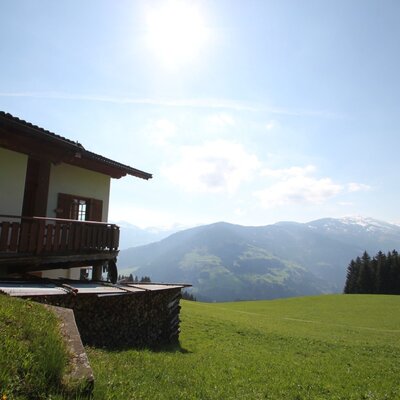 Flecklhütte with balcony, located on a green meadow with a view of the mountains.