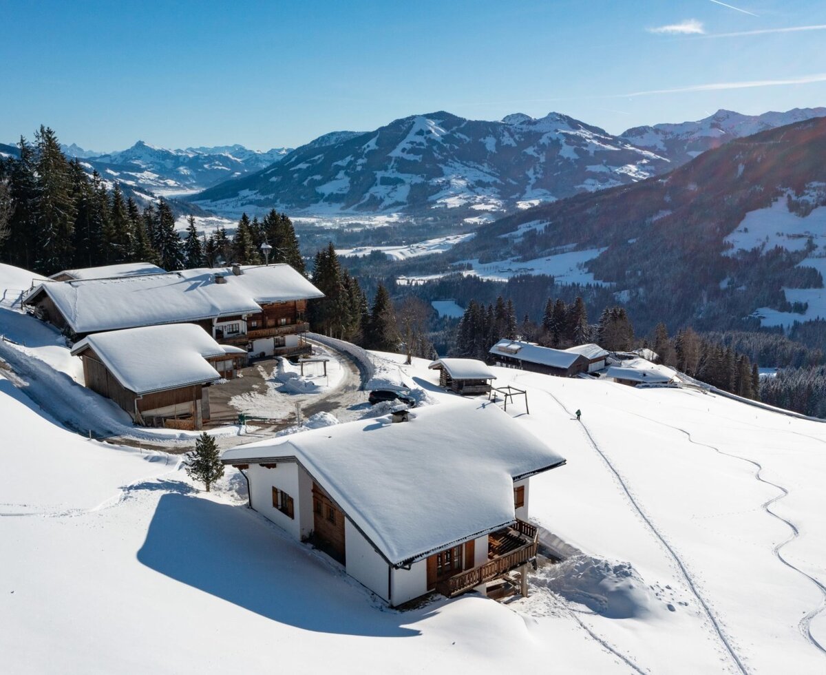 The Flecklhütte, consisting of several snow-covered buildings, embedded in a winter mountain landscape.