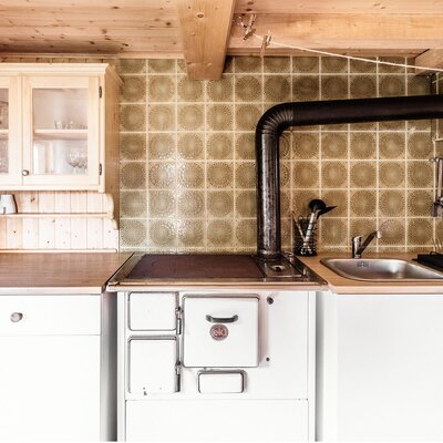 The kitchen in the Alpine Hut is equipped with a wood-fired range, sink, wooden countertops, and a tiled backsplash.