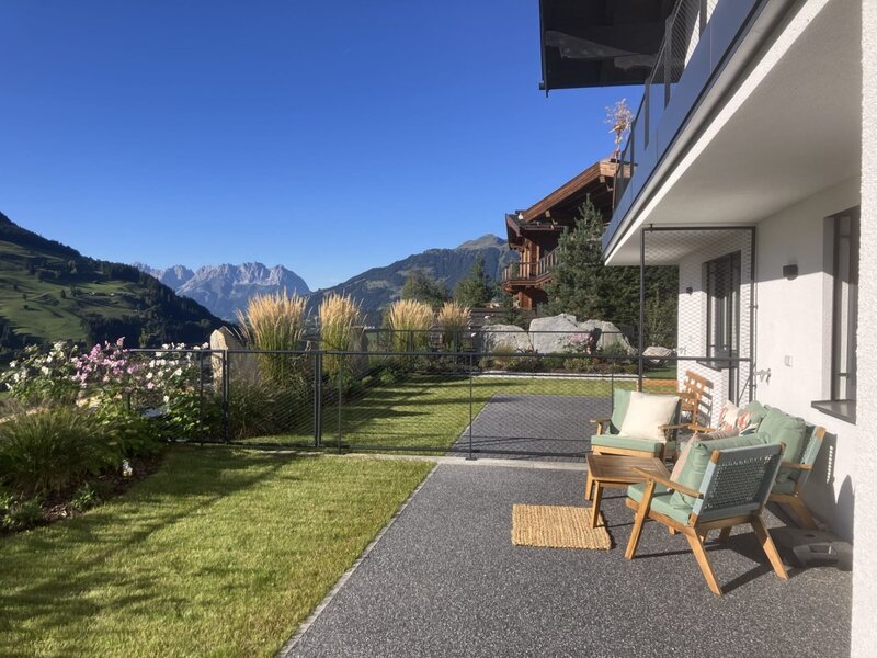 The bed and breakfast's sunny terrace features inviting outdoor seating, a manicured lawn, and beautiful mountain views.