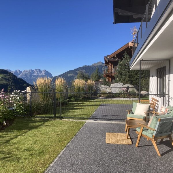 The bed and breakfast's sunny terrace features inviting outdoor seating, a manicured lawn, and beautiful mountain views.