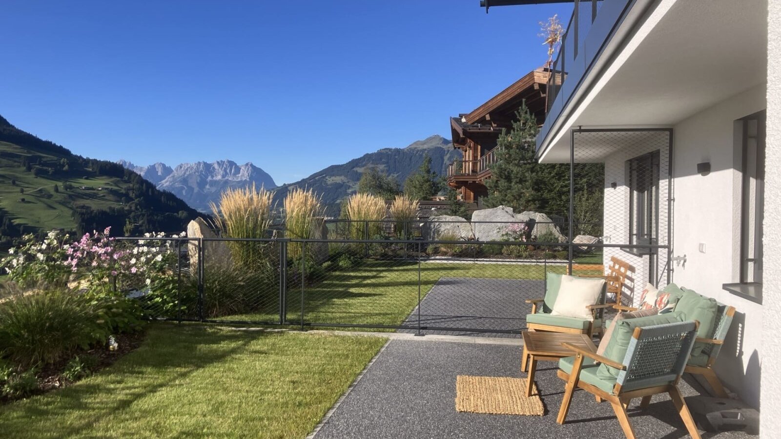 The bed and breakfast's sunny terrace features inviting outdoor seating, a manicured lawn, and beautiful mountain views.