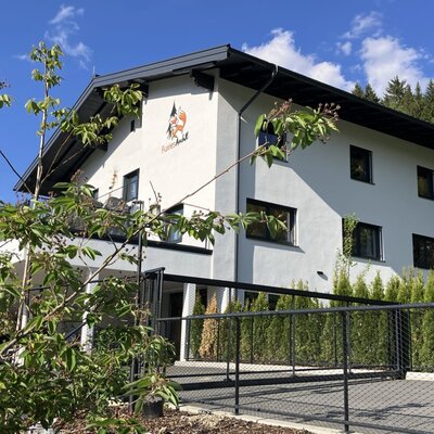The inviting bed and breakfast is nestled in green surroundings under a bright blue sky.