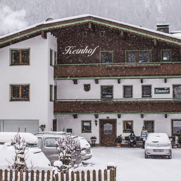 The Kernhof Farm House exterior, featuring balconies and a snow-covered parking area in winter.