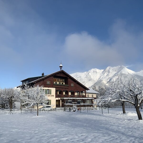 The Farm House exterior in winter, surrounded by snow-covered orchard trees and mountains. The Farm House exterior in winter, surrounded by snow-covered orchard trees and mountains.