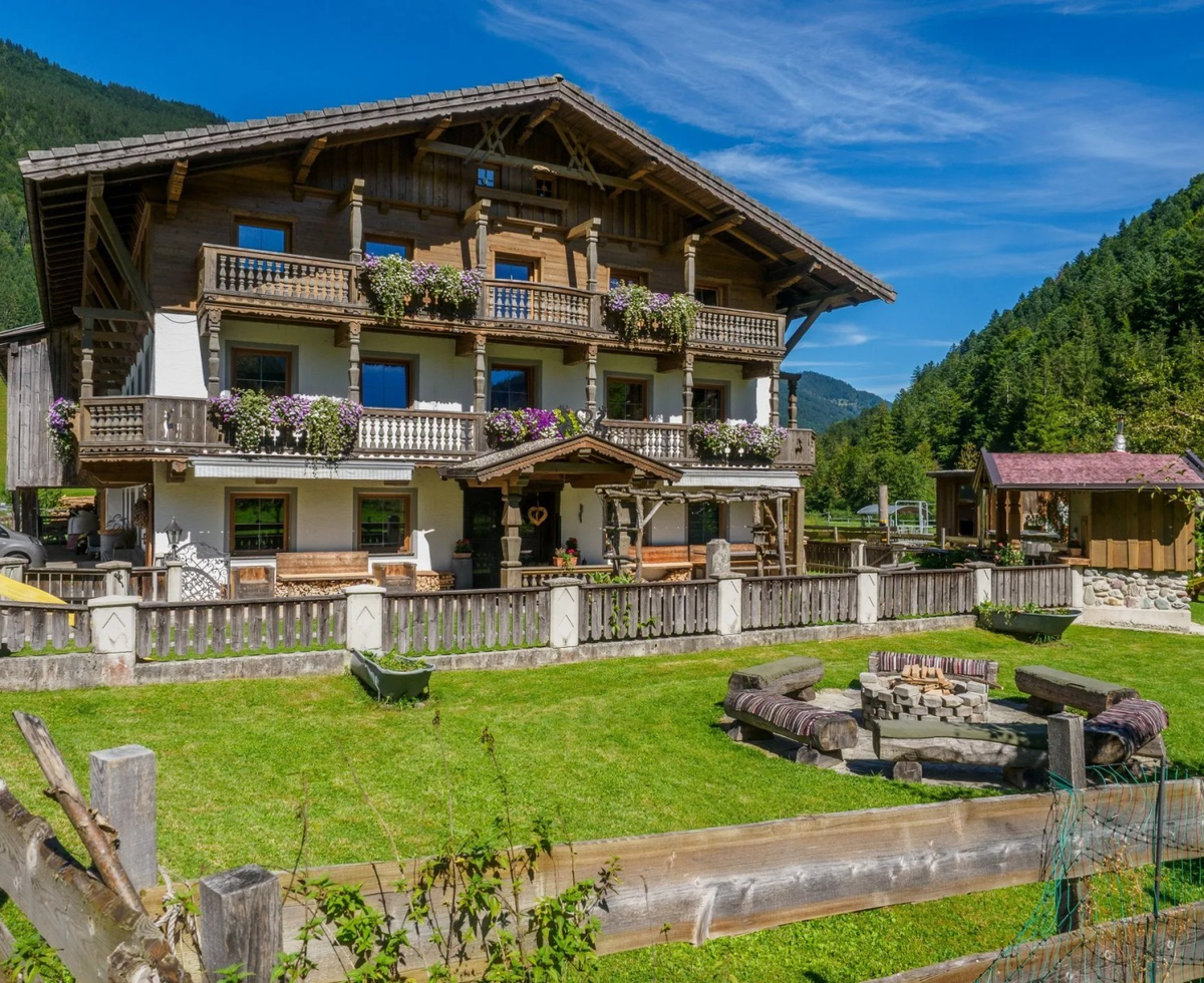 The charming apartment building featuring traditional wooden balconies, a manicured lawn, and an inviting outdoor fire pit.