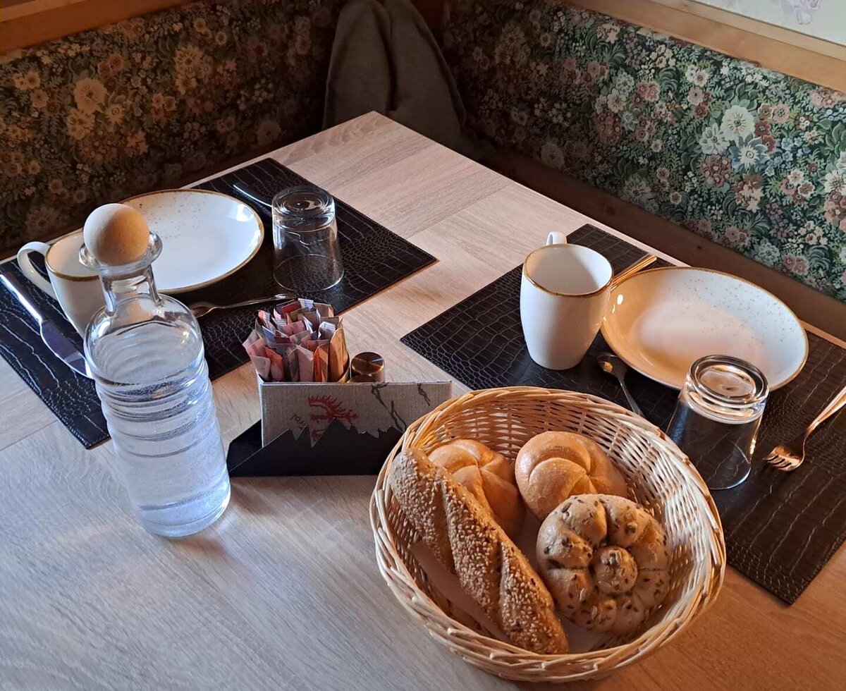 An inviting breakfast table at the farmhouse, set with fresh bread rolls and cozy corner seating.