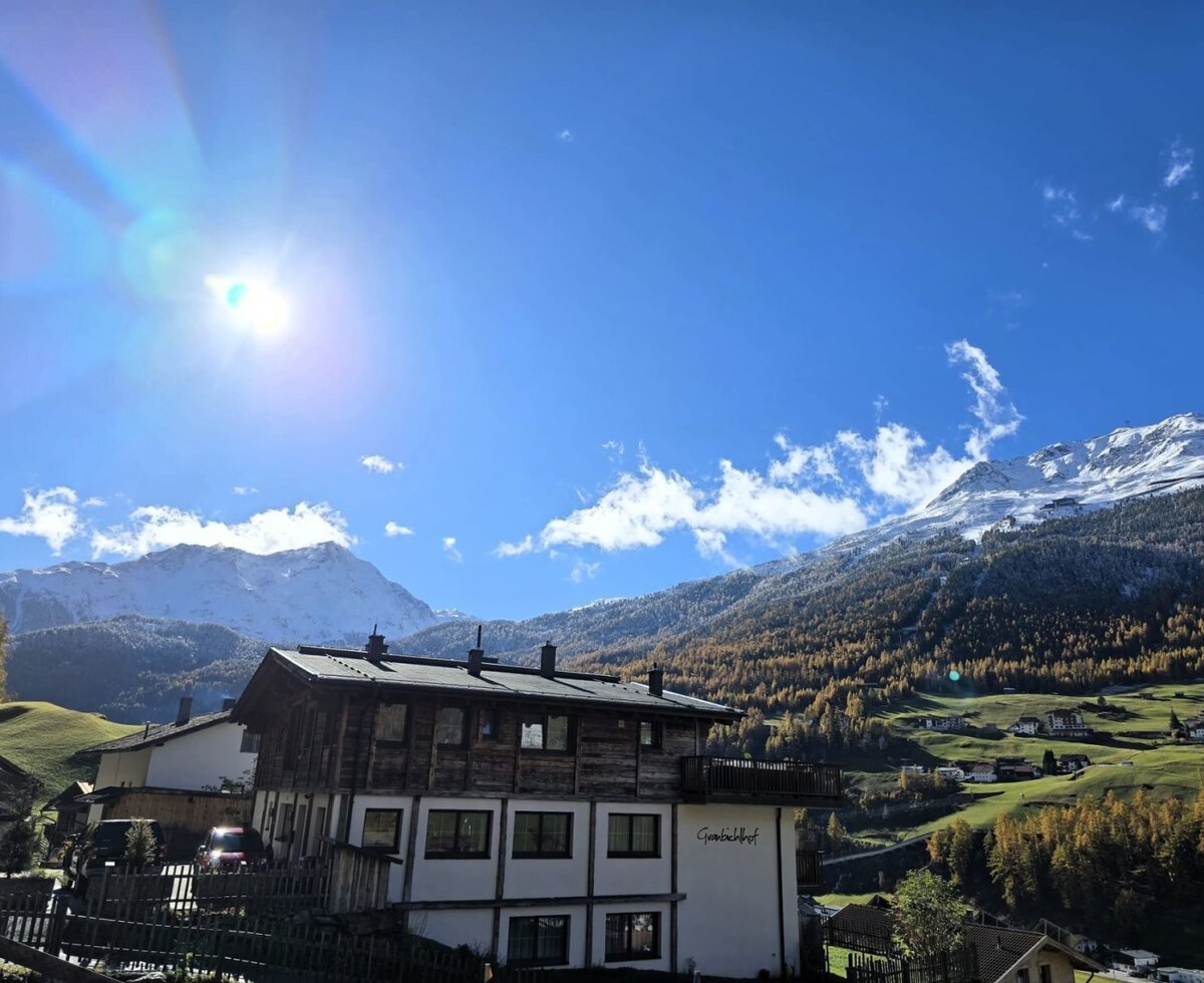The Bauernhof with a view of the snow-capped mountains and the valley under a blue sky.