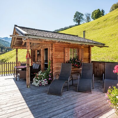The Farm House offers a wooden deck equipped with sun loungers and an outdoor dining area, set against hillside and mountain scenery.