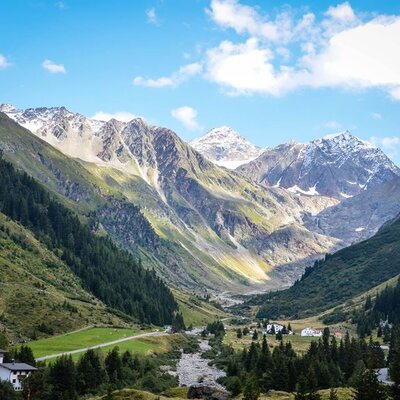 A view of the mountain valley surrounding the Farm House, with green hillsides and snow-capped peaks.