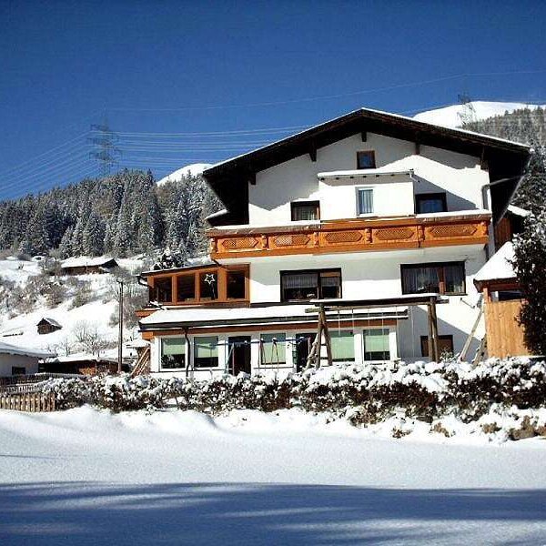 The multi-story Farm House features balconies, a ground-floor conservatory, and is set against a snowy mountain backdrop.