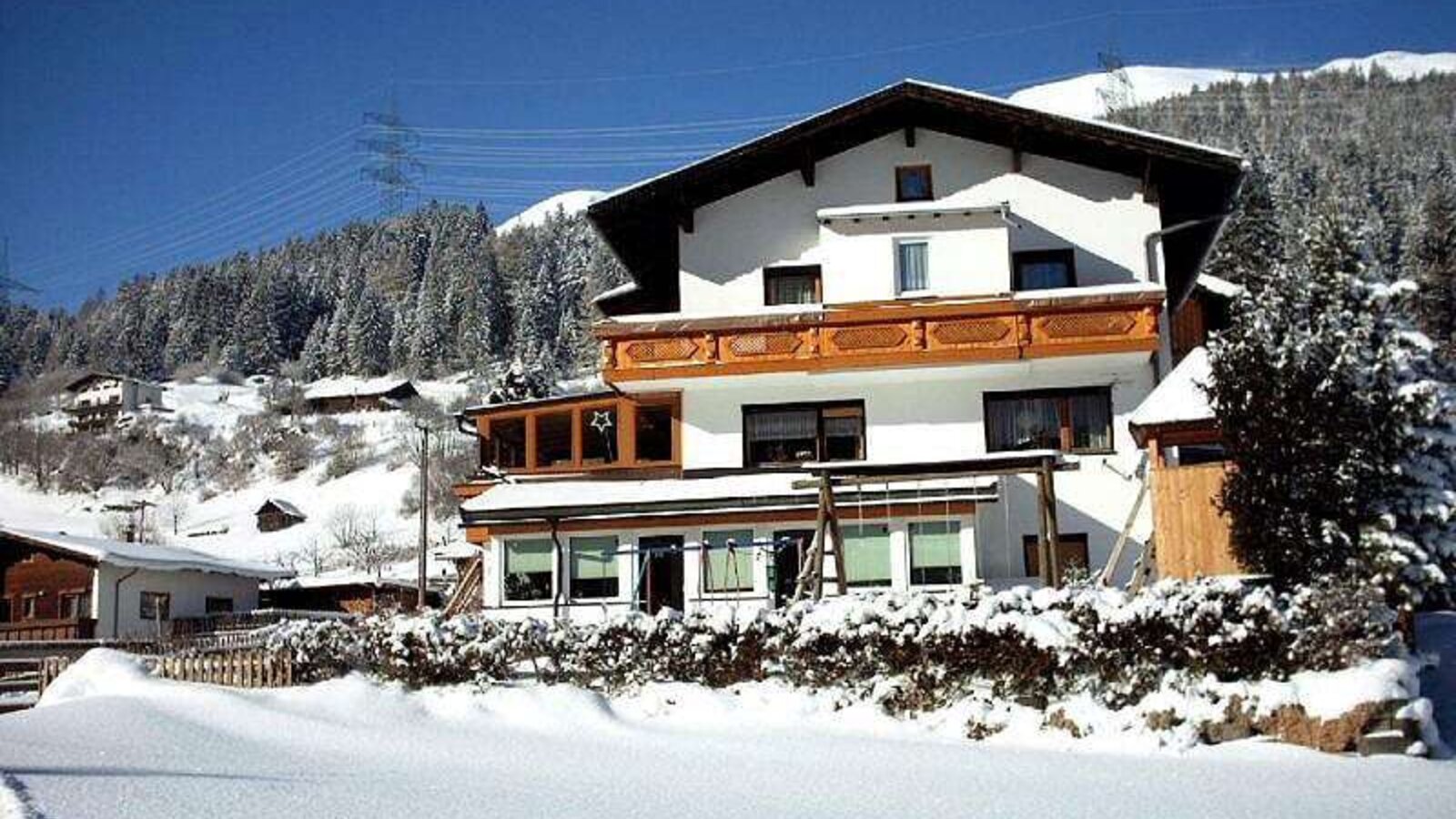 The multi-story Farm House features balconies, a ground-floor conservatory, and is set against a snowy mountain backdrop.