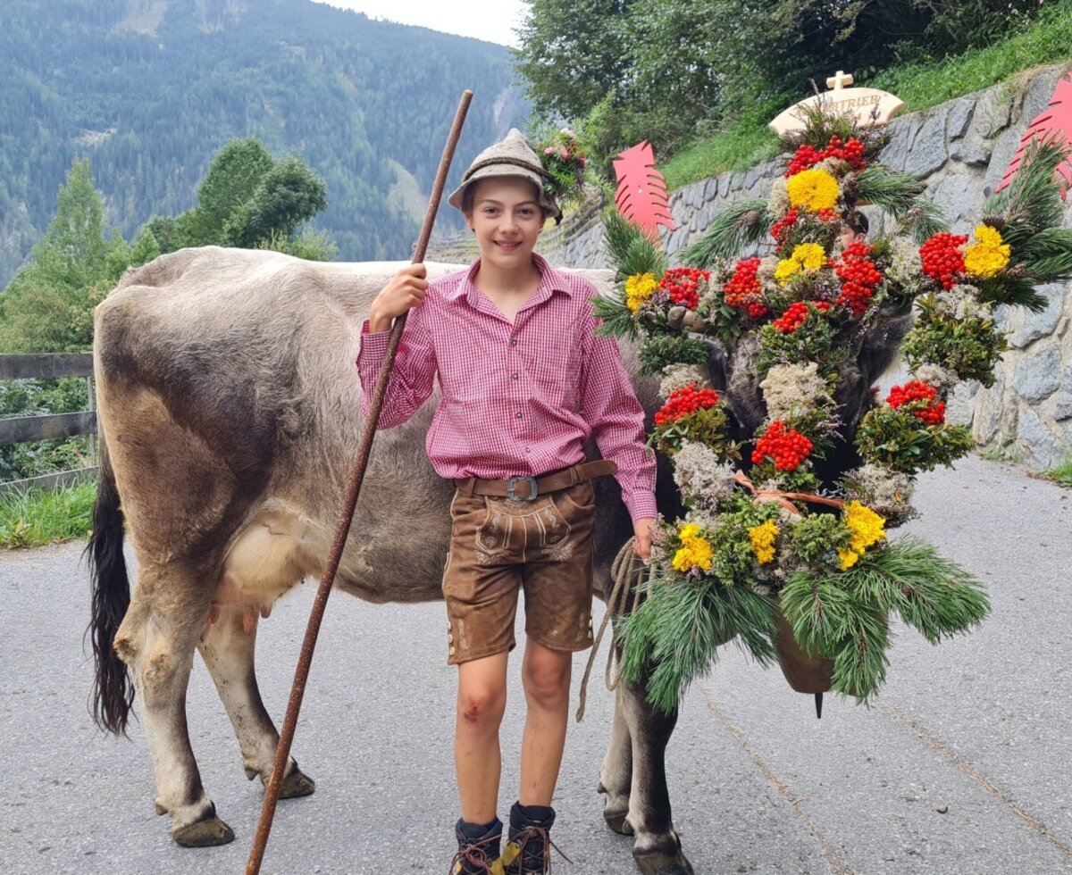 A boy in traditional attire with a festively decorated cow, reflecting traditional farmhouse life.