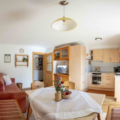 Living and kitchen area of the farmhouse with a dining table, sofa, and fully equipped kitchenette.