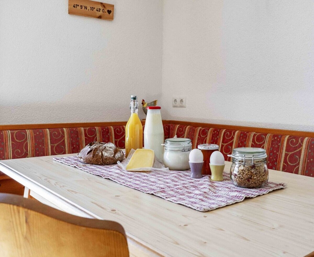 Breakfast table in the farmhouse with fresh bread, cheese, milk, juice, eggs, and muesli.