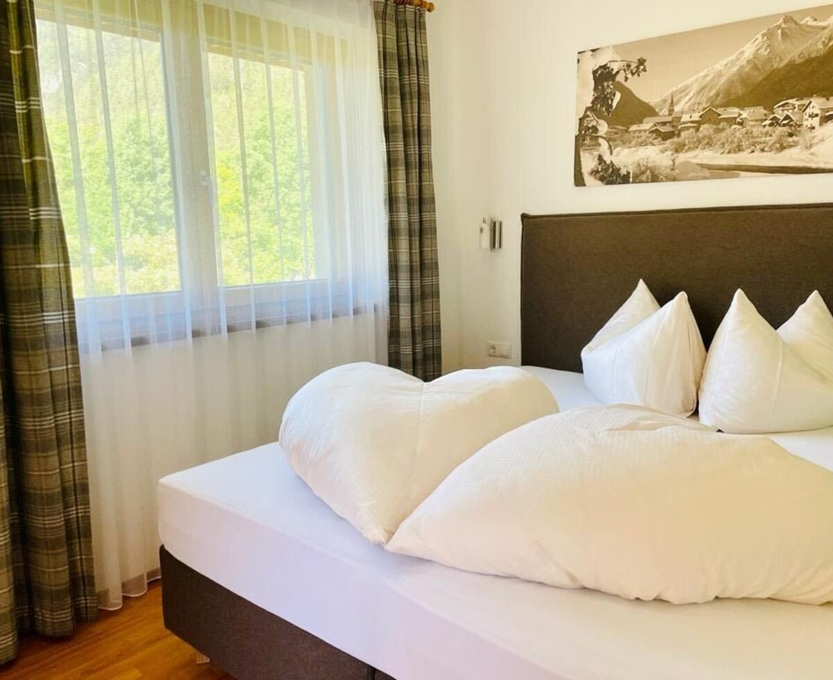 Double bed in the farmhouse room with a window view of greenery and a mountain landscape print.