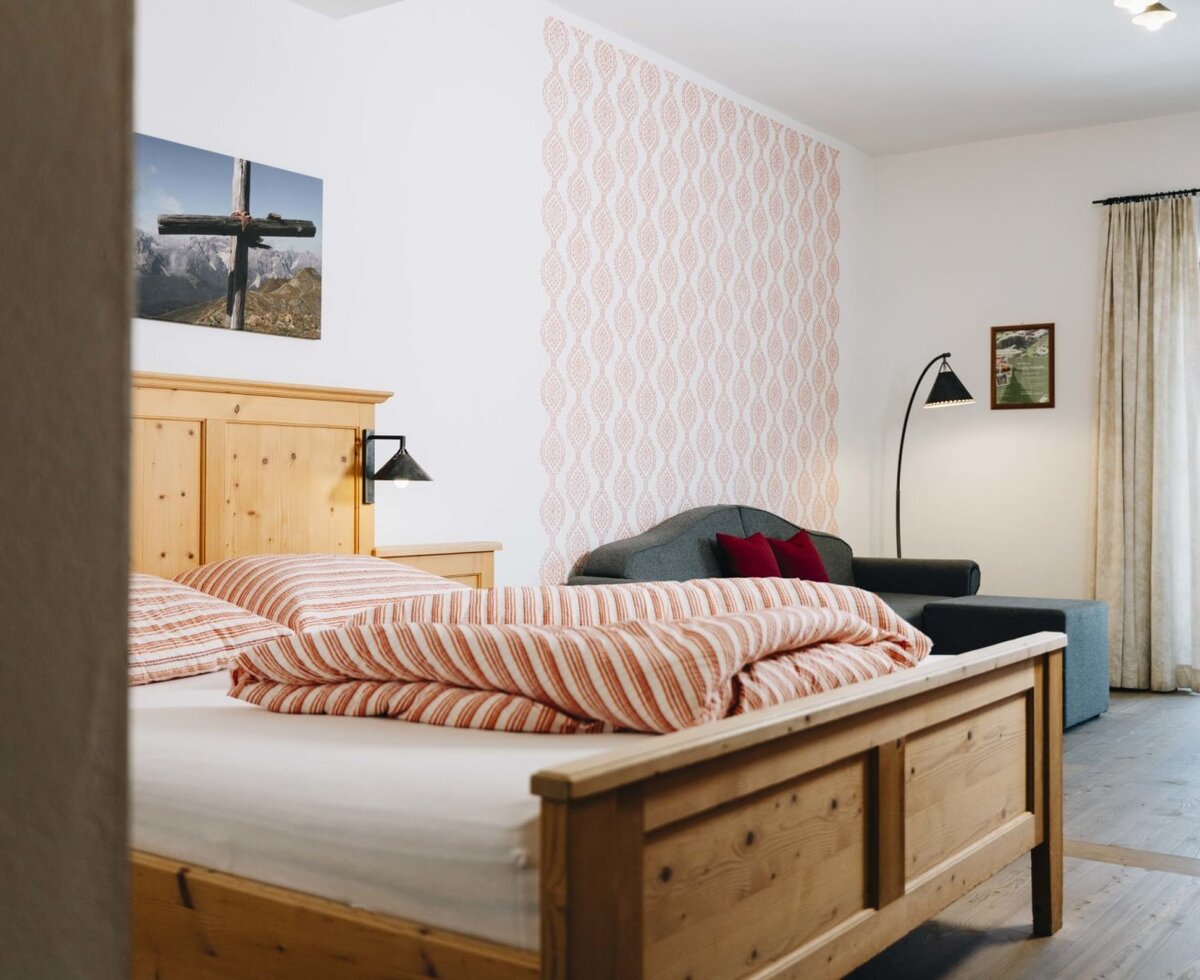 Bedroom in the farmhouse featuring a wooden bed, a sofa, and balcony access.