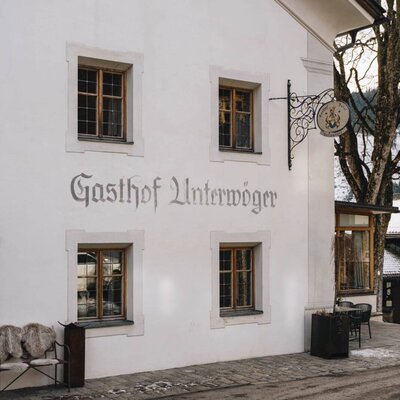 Exterior view of Gasthof Unterwöger featuring its sign, windows, and an outdoor seating area.