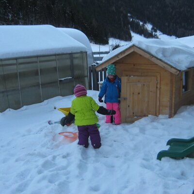 The Farm House offers an outdoor play area for children, including a wooden playhouse and a slide, seen here in the snow.