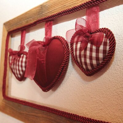 Heart-shaped decorative cushions with ribbons on a wall in the Farm House.