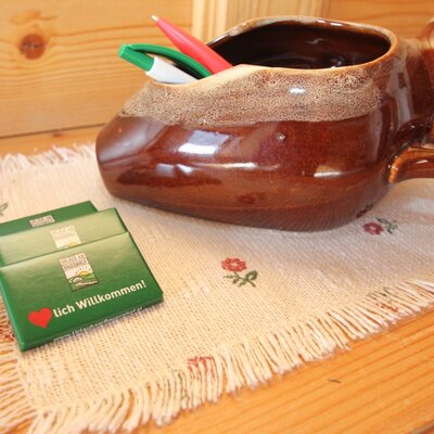 Welcome amenities in the farmhouse, featuring a ceramic pen holder and small welcome gifts on an embroidered placemat.