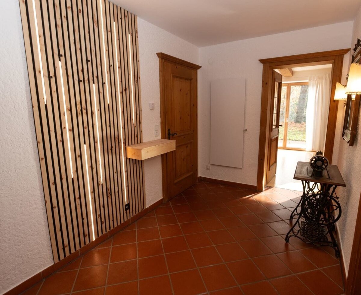 Entrance area of the Apartment featuring a modern wooden slatted wall with integrated lighting and terracotta tiles.