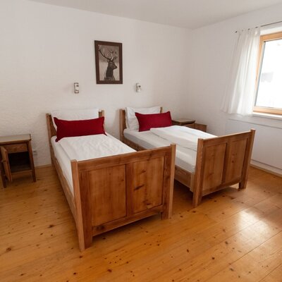Bedroom in the Bed and Breakfast with two single beds, wooden floors, and a window.