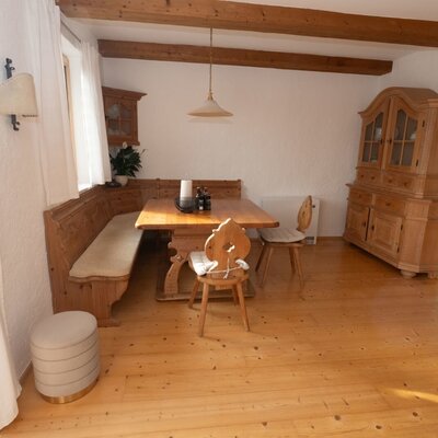 The dining area in the Apartment features a wooden table, corner bench, and traditional wooden chairs under exposed ceiling beams.