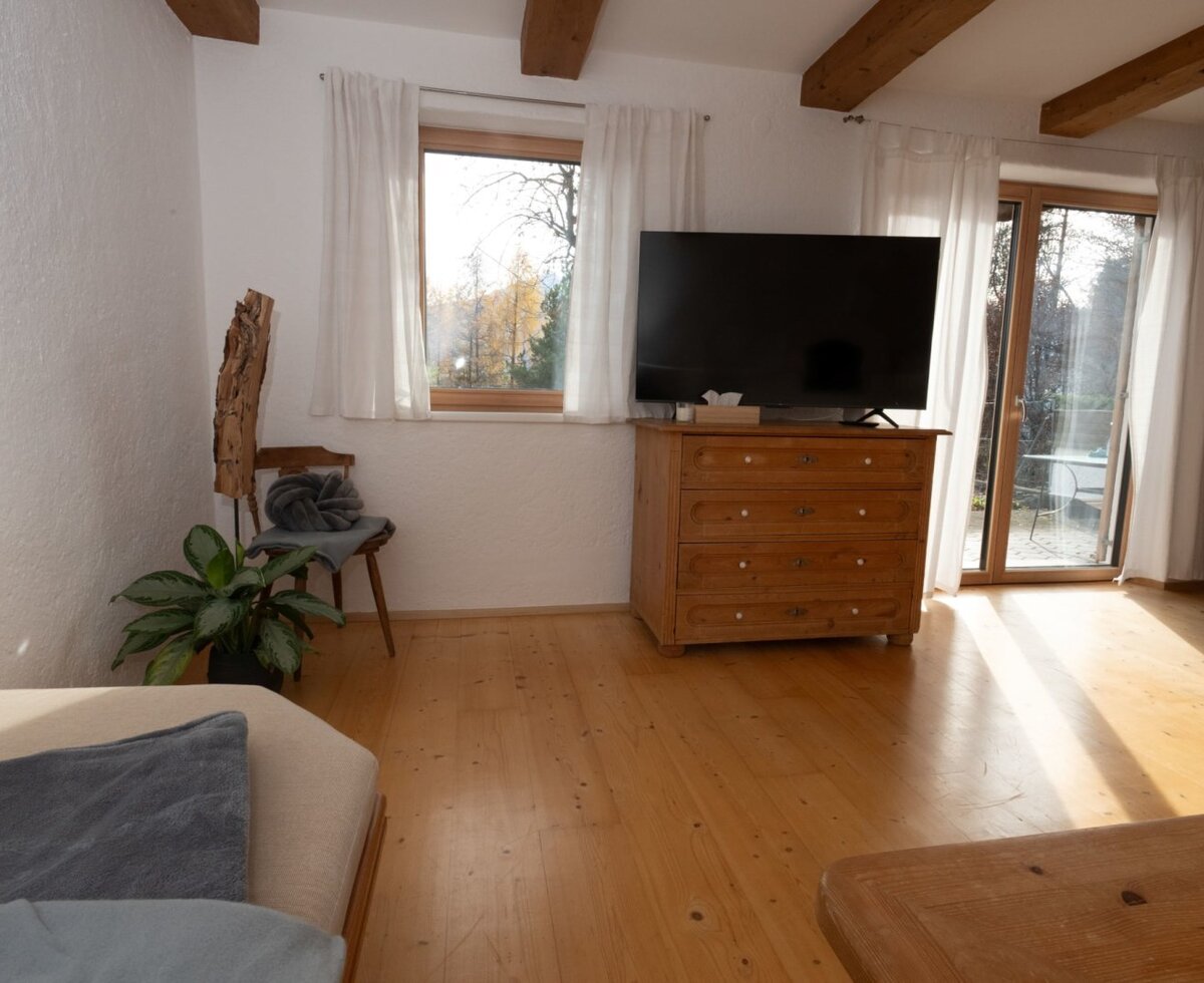 Living area of the Apartment with a TV, wooden dresser, and direct access to the terrace.