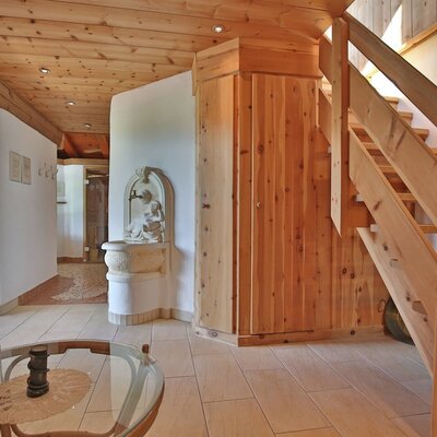 Wooden staircase and hallway in the farmhouse, featuring a wooden ceiling and a decorative wall fountain.