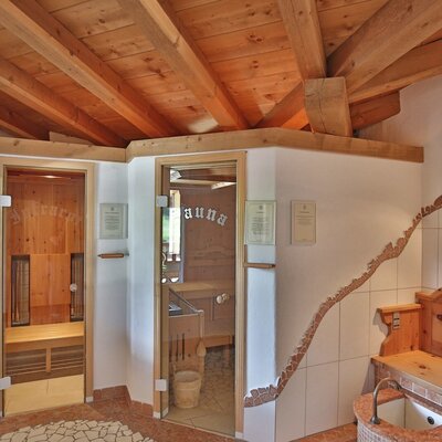 The sauna area in the farmhouse, featuring an infrared cabin, a traditional sauna, and a wooden bench with a sink.