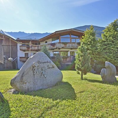 Exterior view of the Leneler farmhouse with a lawn and the inscribed stone.