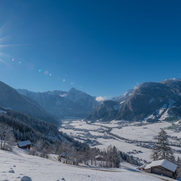 A sunlit winter view of the snow-covered Zillertaler Alps valley and a village from the Farm House.