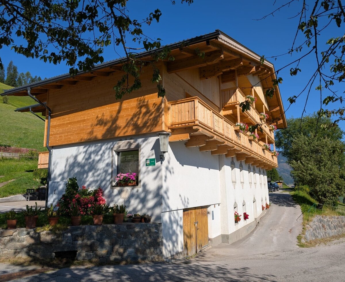 Exterior view of the farmhouse, featuring wooden balconies with flower boxes.