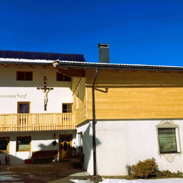 Exterior view of the Neuhauserhof farmhouse with balconies and solar panels on the roof. Exterior view of the Neuhauserhof farmhouse with balconies and solar panels on the roof.