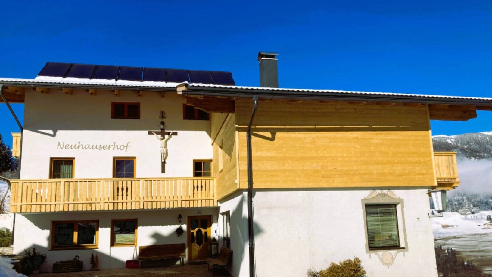 Exterior view of the Neuhauserhof farmhouse with balconies and solar panels on the roof.