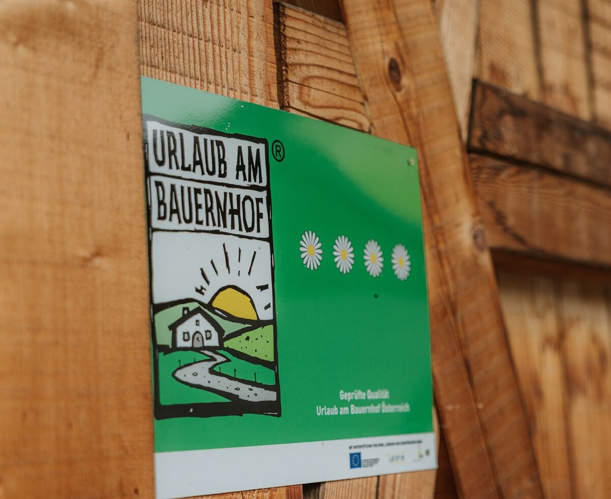 The official 'Urlaub am Bauernhof' quality seal with 4 daisies at the farmhouse.