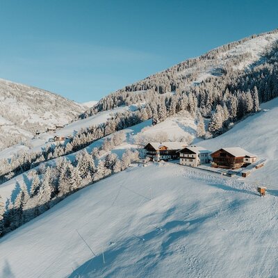 The farmhouse exterior in a snowy mountain landscape, surrounded by forests.