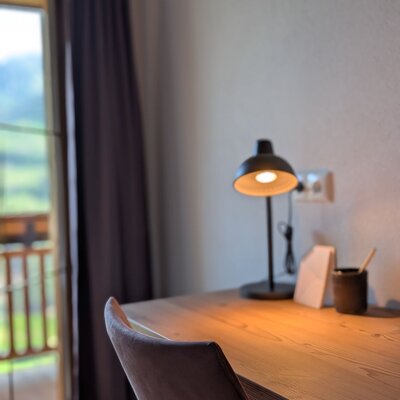 Desk in the farmhouse with a lamp and chair, featuring balcony access and mountain views.