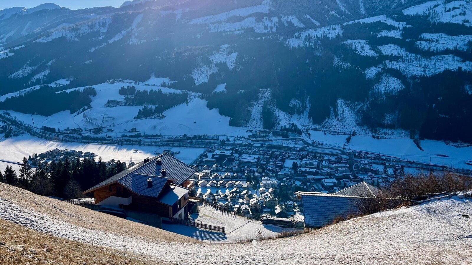 View from the farmhouse of the snow-covered mountain landscape and the valley with the village.