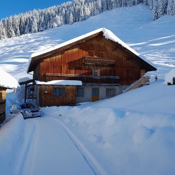 The wooden Alpine Hut in a snow-covered mountain landscape, featuring balconies and a snow-cleared driveway. The wooden Alpine Hut in a snow-covered mountain landscape, featuring balconies and a snow-cleared driveway.