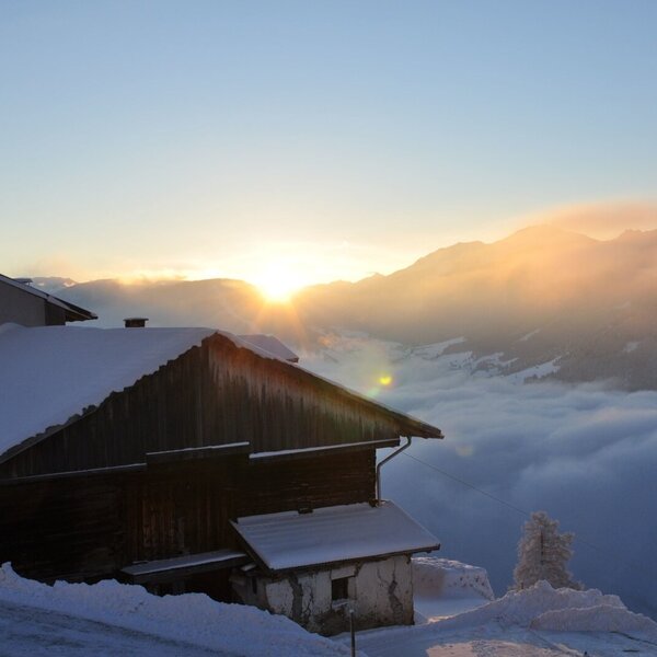 The Farm House in a snowy mountain landscape, with a sunrise breaking through a cloud layer.