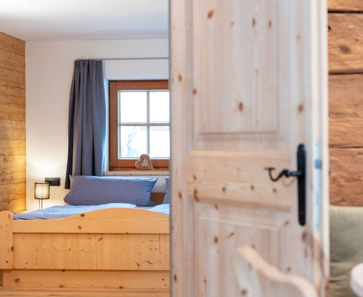 Bedroom in the apartment with a wooden bed, window, and wooden accent wall.