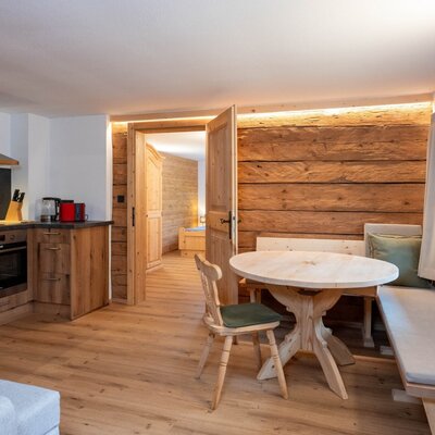 Kitchen and dining area of the apartment with modern appliances, oven, and a wooden table with corner bench.
