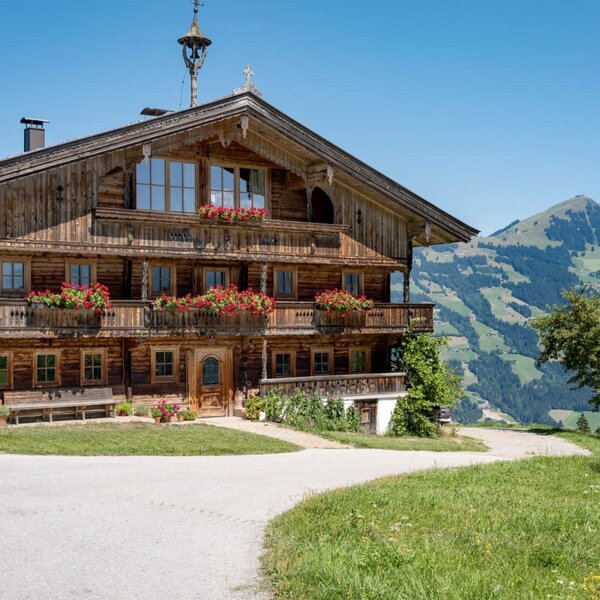 The apartments' idyllic farmhouse featuring flower-adorned balconies against a scenic mountain backdrop.