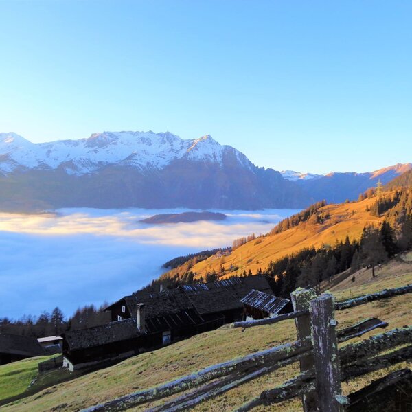 View of the snow-capped mountains and a cloud-filled valley from the Alpine Hut's hillside setting. View of the snow-capped mountains and a cloud-filled valley from the Alpine Hut's hillside setting.