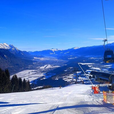 Ski slope Oberperfuss with a gondola lift, offering a panoramic view of the snow-covered valley and surrounding mountains.