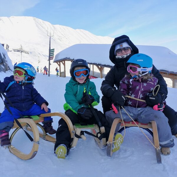 A family enjoying sledding on a snowy mountain slope, showcasing winter activities available for guests at the Farm House.
