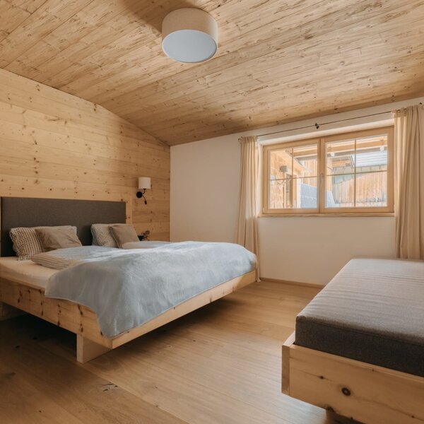Bedroom in the Ferienwohnung featuring a double bed, a daybed, and wooden paneling.