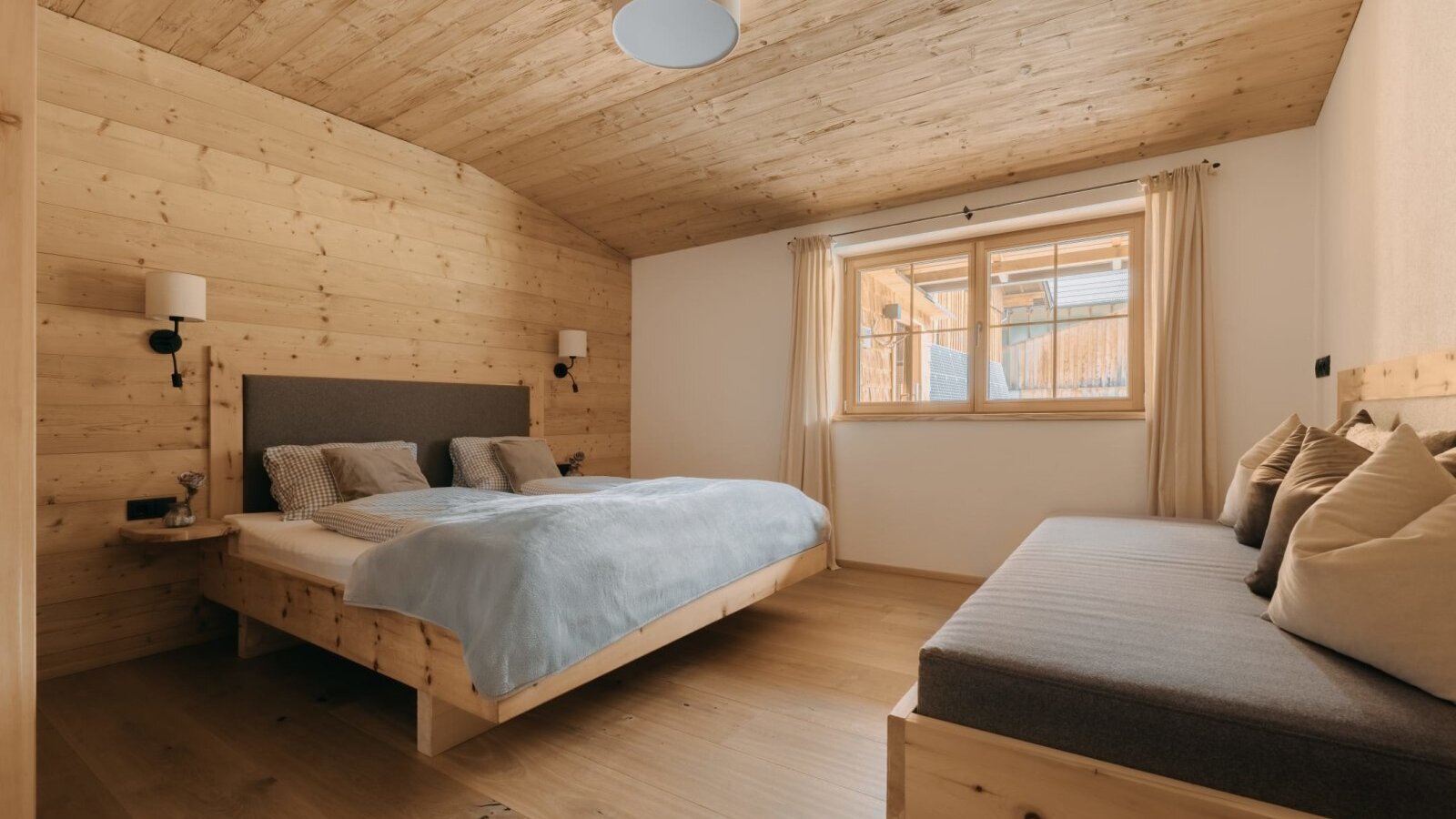 Bedroom in the Ferienwohnung featuring a double bed, a daybed, and wooden paneling.